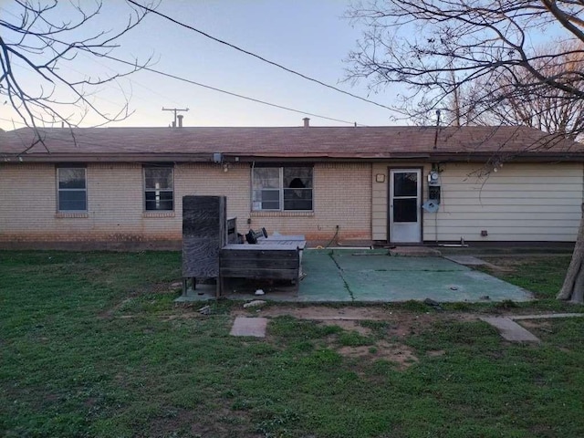 rear view of house with a patio, a lawn, and brick siding