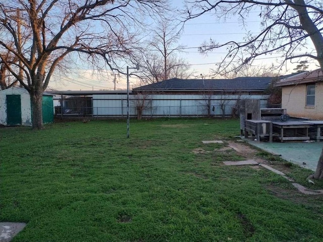 yard at dusk with an outbuilding, a fenced backyard, and a storage shed