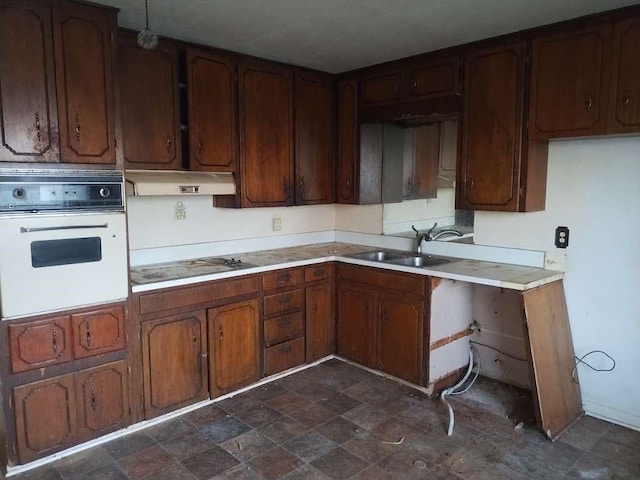 kitchen with oven, electric cooktop, under cabinet range hood, a sink, and light countertops