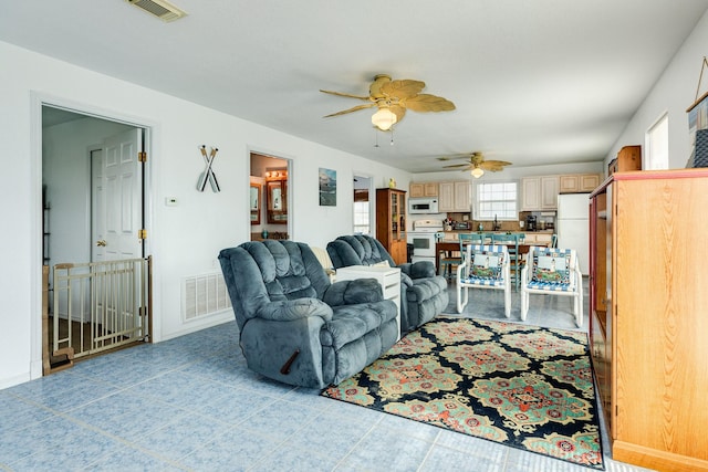 living area featuring visible vents, baseboards, and a ceiling fan