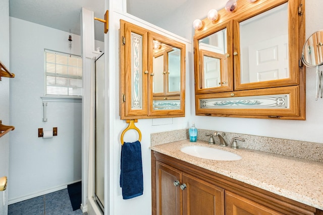 bathroom featuring vanity, a shower stall, and baseboards