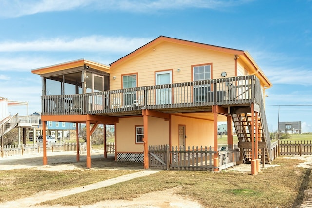 rear view of house with stairs, a deck, fence, and a sunroom