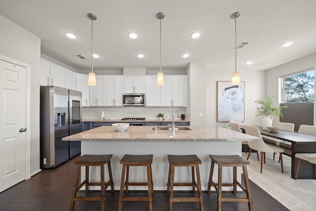 kitchen featuring a sink, a breakfast bar area, white cabinets, and stainless steel appliances