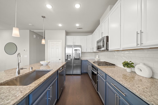 kitchen with a sink, blue cabinetry, dark wood finished floors, stainless steel appliances, and white cabinets