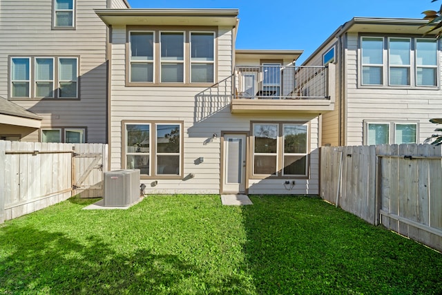 back of house with a yard, a fenced backyard, a balcony, and central AC