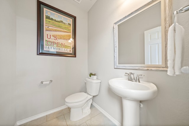 half bath with a sink, baseboards, toilet, and tile patterned flooring