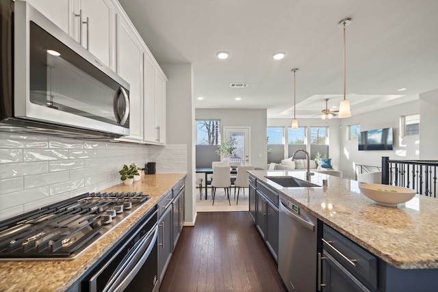 kitchen featuring white cabinets, open floor plan, appliances with stainless steel finishes, and a sink