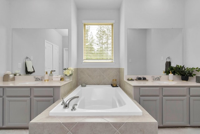 bathroom with a sink, two vanities, and a bath