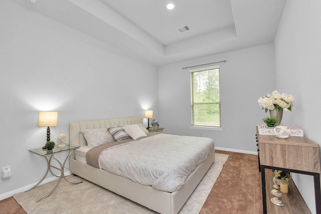 bedroom featuring visible vents, carpet flooring, a raised ceiling, and baseboards