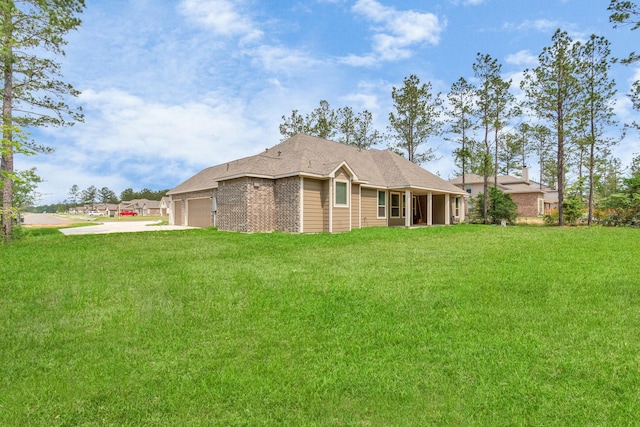 back of house featuring a yard, brick siding, a garage, and driveway