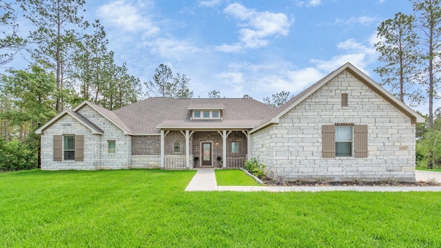 view of front facade with brick siding, a shingled roof, and a front lawn