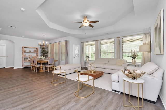 living room featuring visible vents, ceiling fan with notable chandelier, a raised ceiling, and wood finished floors