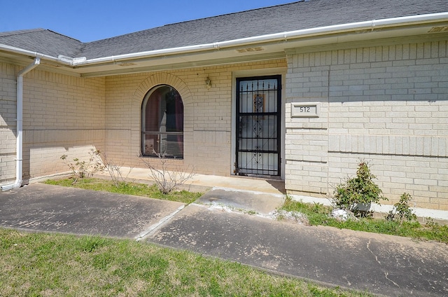 property entrance with brick siding and roof with shingles