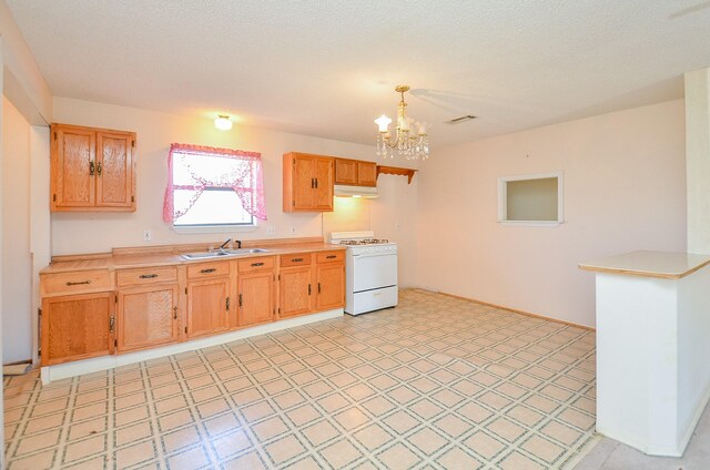 kitchen featuring a notable chandelier, white gas stove, under cabinet range hood, light countertops, and light floors