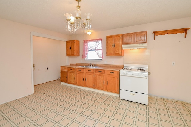 kitchen featuring light floors, gas range gas stove, a sink, light countertops, and under cabinet range hood