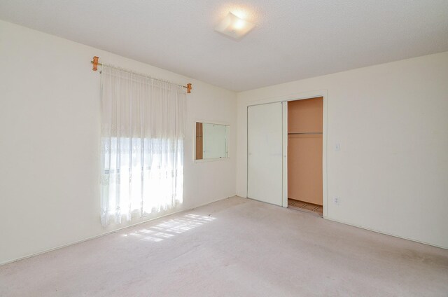 unfurnished bedroom with a closet and light carpet