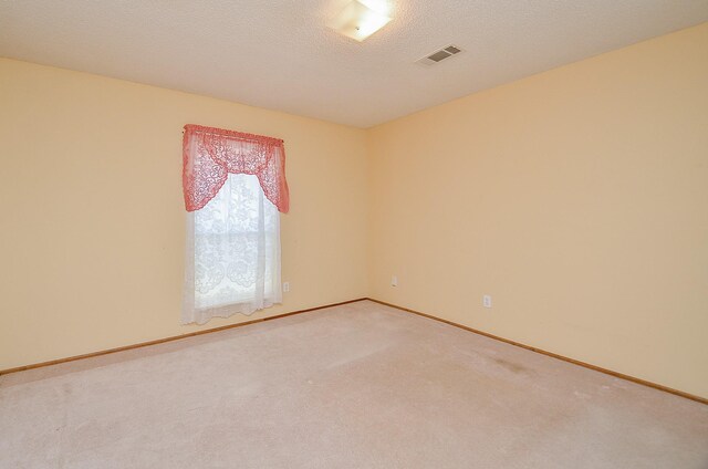 carpeted empty room with visible vents, a textured ceiling, and baseboards