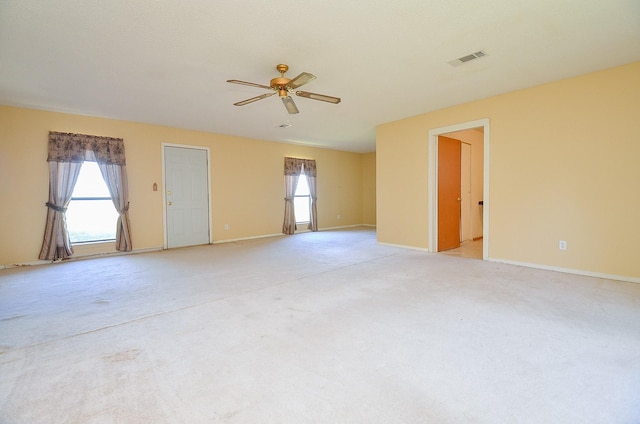 spare room with ceiling fan, visible vents, a wealth of natural light, and light carpet