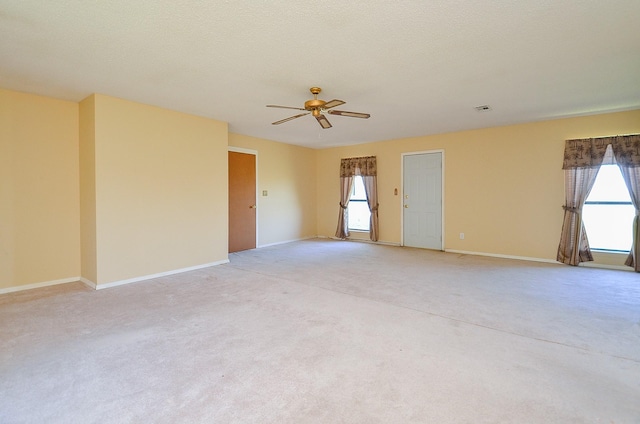 unfurnished room featuring light carpet, a textured ceiling, and baseboards