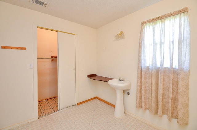 bathroom with tile patterned floors, visible vents, a textured ceiling, and baseboards