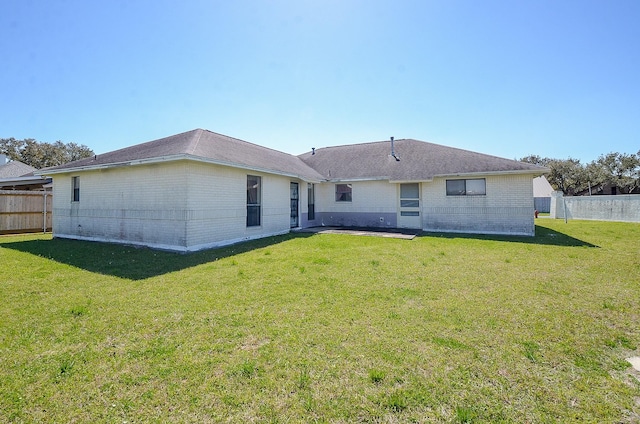 back of house with fence, brick siding, and a lawn