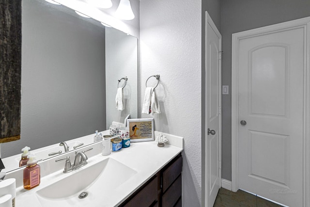 bathroom featuring tile patterned flooring, vanity, and a textured wall