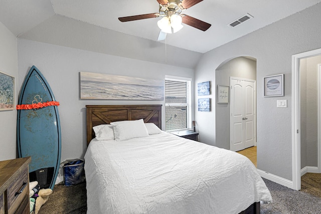 bedroom with baseboards, visible vents, carpet floors, lofted ceiling, and arched walkways