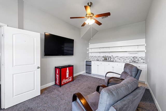 living area featuring ceiling fan, baseboards, and light carpet