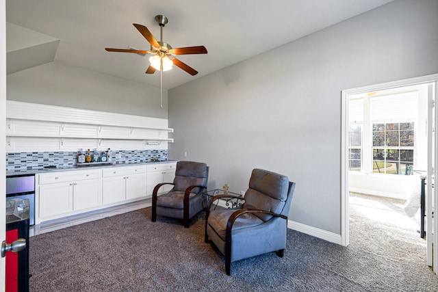 sitting room featuring vaulted ceiling, ceiling fan, baseboards, and dark colored carpet