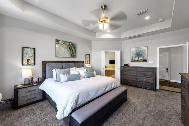 carpeted bedroom featuring ensuite bath, a raised ceiling, recessed lighting, and visible vents