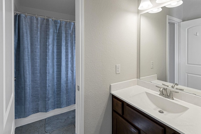 full bathroom featuring a textured wall, tile patterned flooring, vanity, and shower / bath combination with curtain