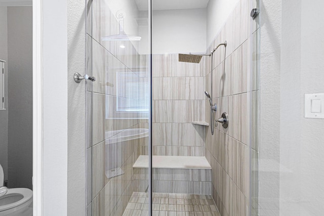 full bathroom featuring toilet, a shower stall, and a textured wall