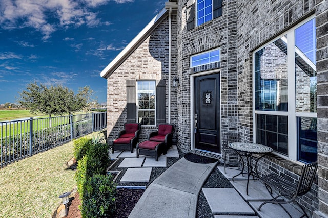 entrance to property with a patio, fence, and brick siding