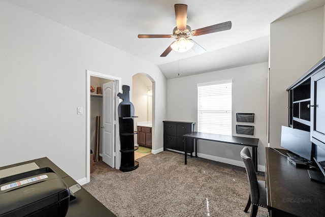 home office with a ceiling fan, baseboards, lofted ceiling, arched walkways, and light carpet