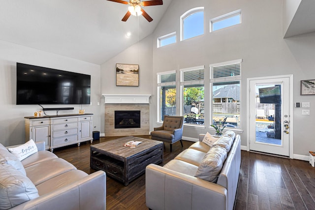 living room featuring baseboards, plenty of natural light, dark wood-style flooring, and a tile fireplace