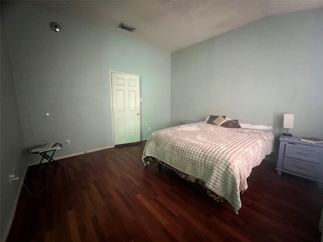 bedroom featuring visible vents, baseboards, lofted ceiling, and wood finished floors