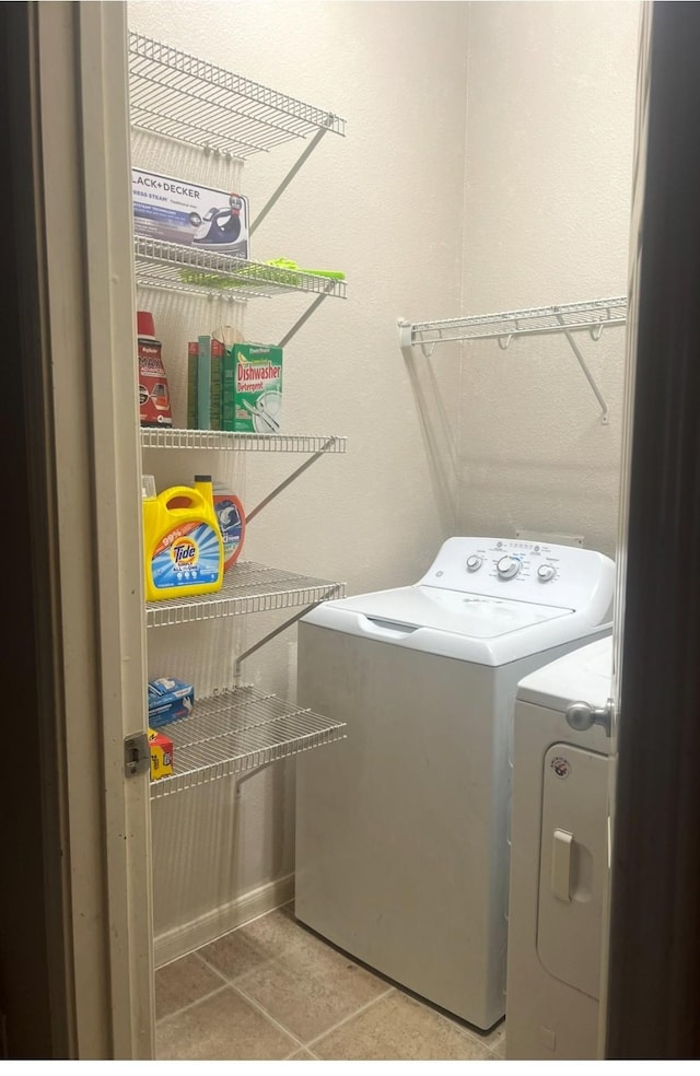 clothes washing area with tile patterned flooring, laundry area, and washer and clothes dryer