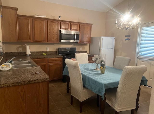 kitchen with dark countertops, stainless steel microwave, brown cabinets, freestanding refrigerator, and a sink