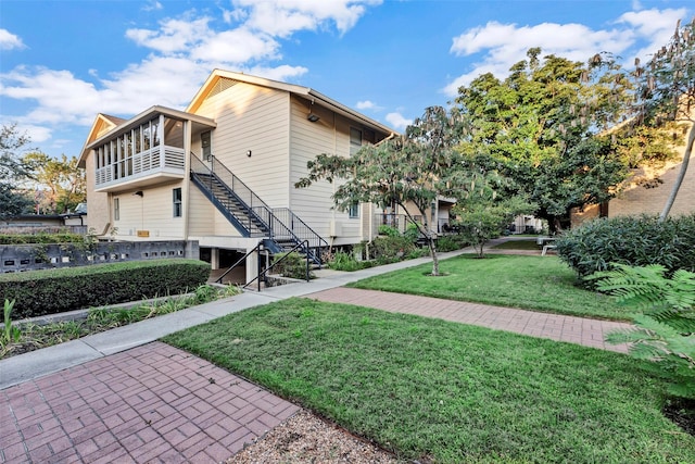 view of property exterior featuring stairway, a yard, and a sunroom