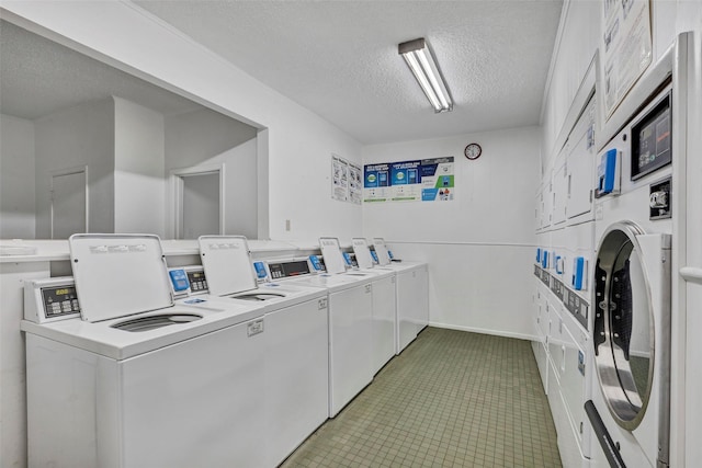 common laundry area featuring a textured ceiling, baseboards, stacked washer and dryer, and washing machine and clothes dryer