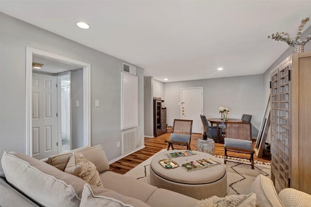 living room with visible vents, recessed lighting, and wood finished floors