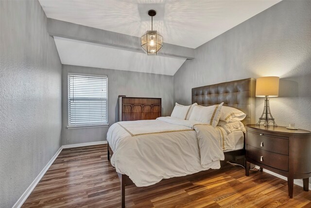 bedroom featuring vaulted ceiling, wood finished floors, baseboards, and a textured wall