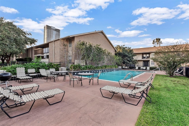 community pool featuring a patio area, a yard, and fence