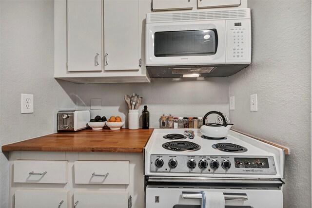 kitchen featuring butcher block countertops, white appliances, white cabinetry, and a textured wall