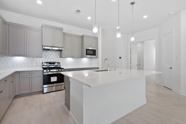 kitchen featuring gas stove, built in microwave, under cabinet range hood, and gray cabinetry