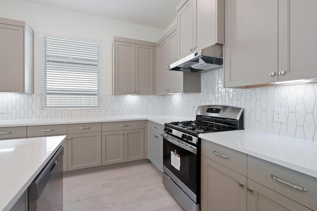 kitchen featuring light countertops, gray cabinets, under cabinet range hood, and stainless steel appliances