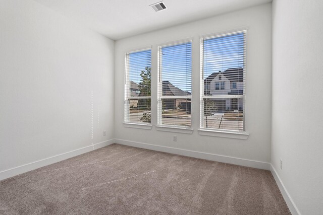 empty room with visible vents, baseboards, and carpet floors