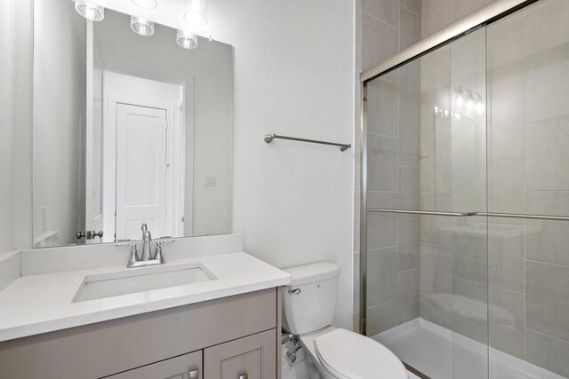 bathroom featuring vanity, toilet, and a stall shower