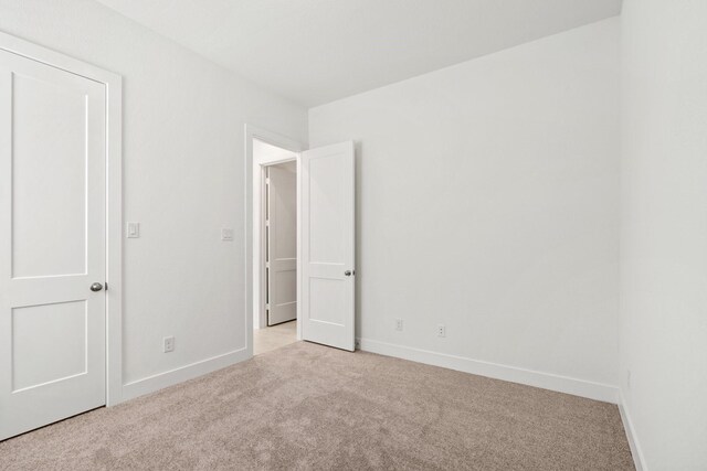 unfurnished bedroom featuring light colored carpet and baseboards