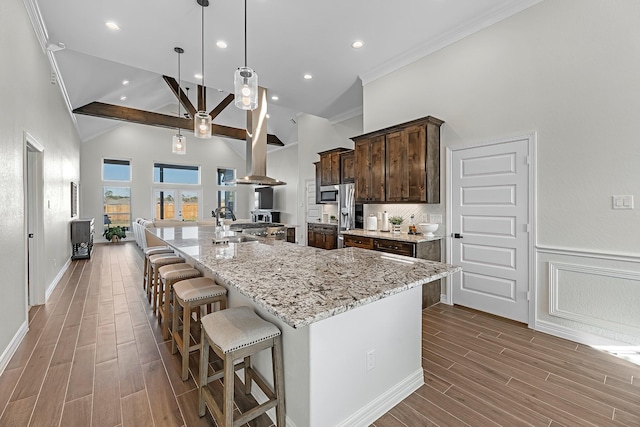 kitchen with wood tiled floor, dark brown cabinetry, a breakfast bar, a large island, and high vaulted ceiling